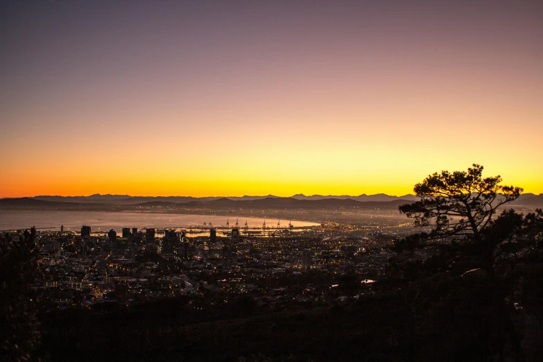 a view of a city from the top of a hill, by Daniel Lieske, pexels contest winner, cape, evening sunset, highly saturated, dim lit