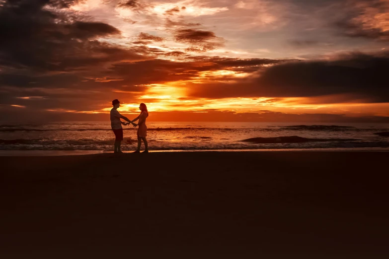 a couple of people standing on top of a sandy beach, by Jesper Knudsen, pexels contest winner, romanticism, red and orange glow, big island, hd footage, ((sunset))