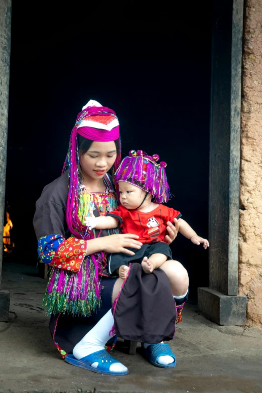 a woman holding a baby in her arms, a picture, inspired by Jin Nong, pexels contest winner, colourful clothing, square, in style of lam manh, slide show