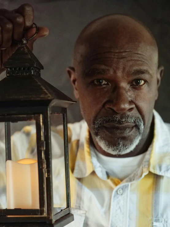a close up of a person holding a lantern, inspired by Gordon Parks, samuel jackson, promo still, old male, concerned
