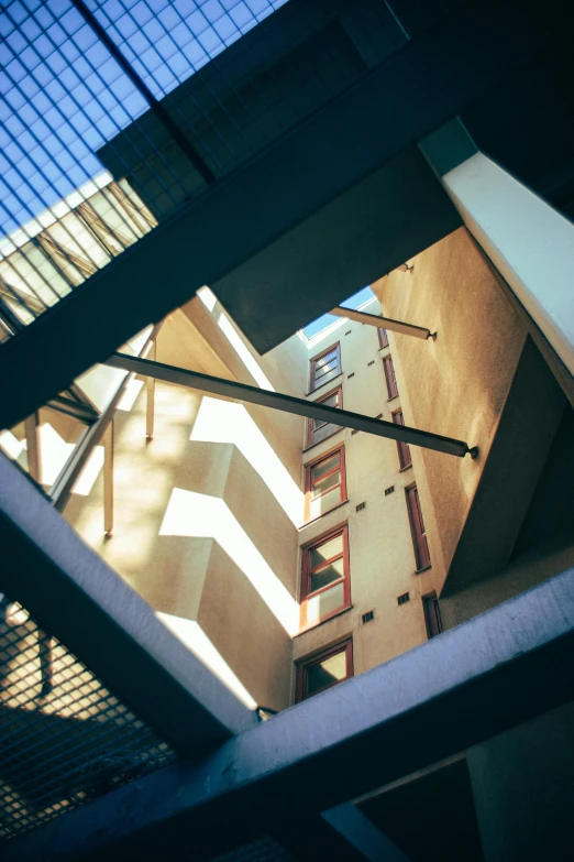 a view of a building through a window, inspired by Ricardo Bofill, unsplash, modernism, volumetric light from below, courtyard, high-angle, stairways