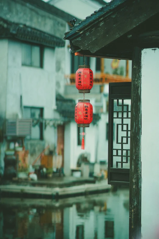 a couple of red lanterns hanging from the side of a building, by Shang Xi, visual art, rainy afternoon, quaint village, professionally color graded, medium-shot