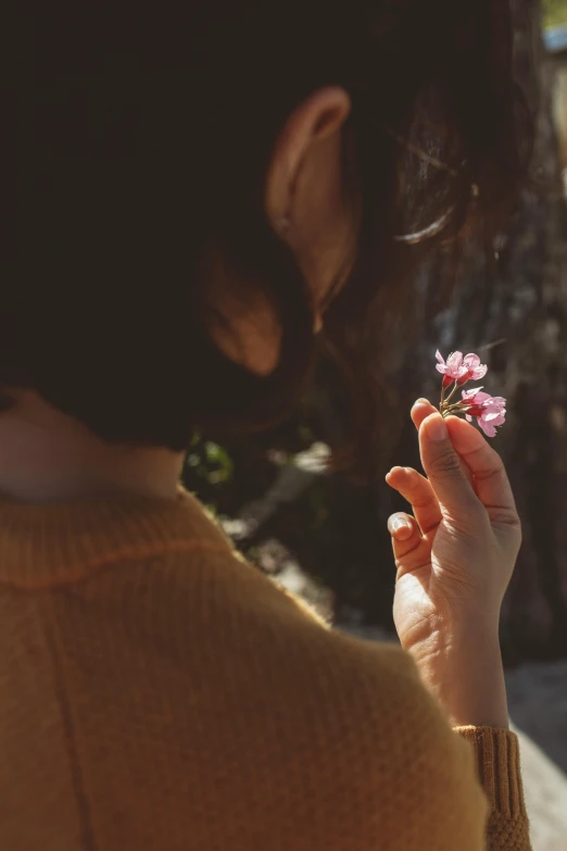 a woman holding a flower in her hand, trending on unsplash, manuka, instagram picture, paul barson, japanese