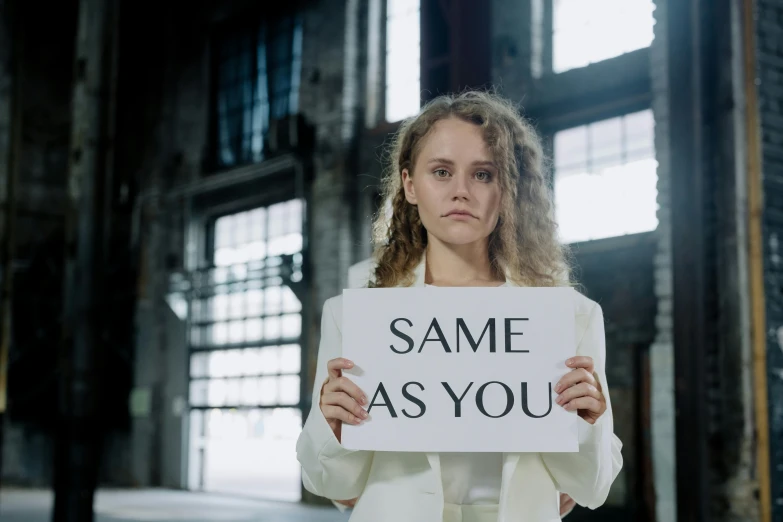 a woman holding a sign that says same as you, inspired by Vanessa Beecroft, unsplash, hermione granger, high quality photo, adam ondra, steins gate