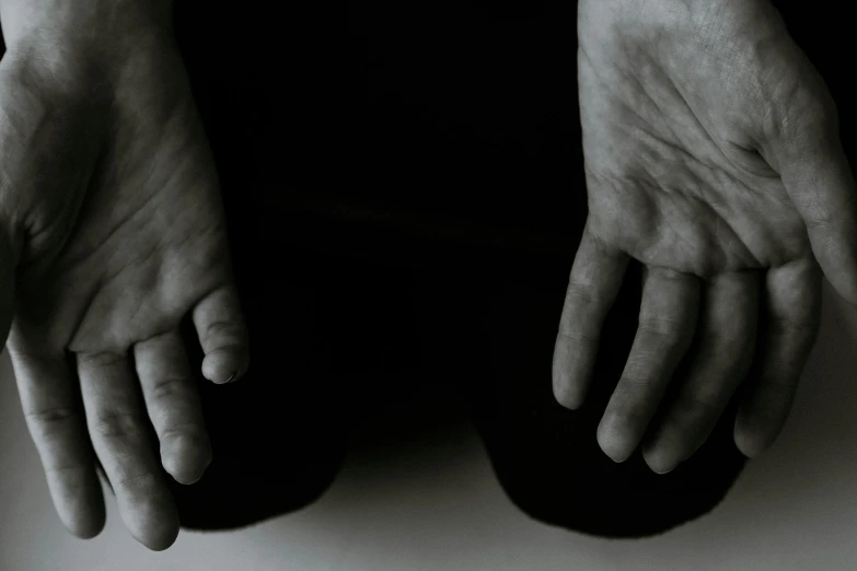 a black and white photo of a person's hands, unsplash, hurufiyya, sitting on the floor, abused, plain background, eery