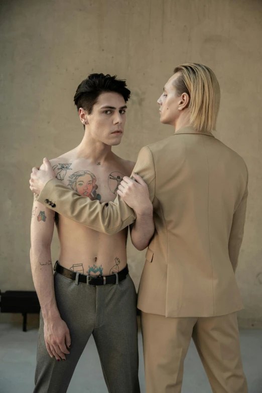 a woman standing next to a man in a suit, a tattoo, nonbinary model, levi ackerman, army, jacket over bare torso