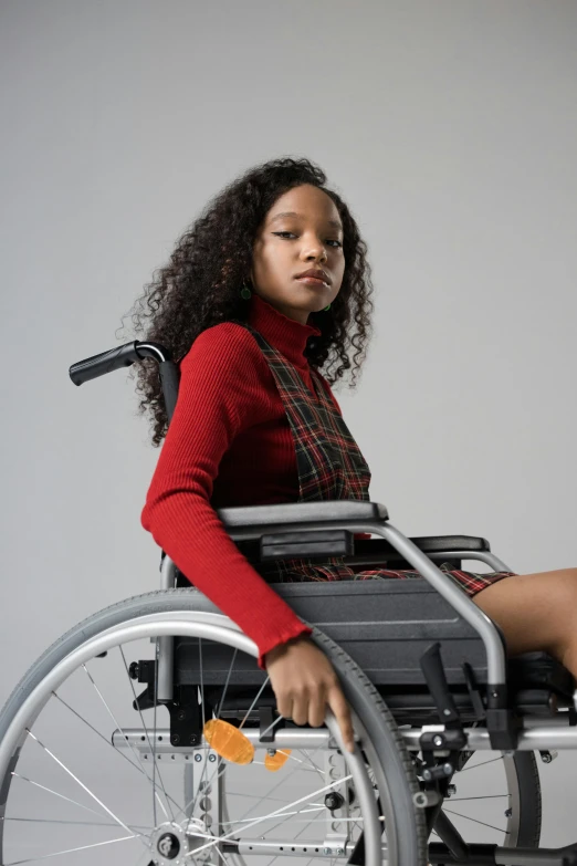 a woman in a wheelchair posing for a picture, an album cover, trending on pexels, black teenage girl, wearing a red plaid dress, wearing a turtleneck and jacket, professional modeling