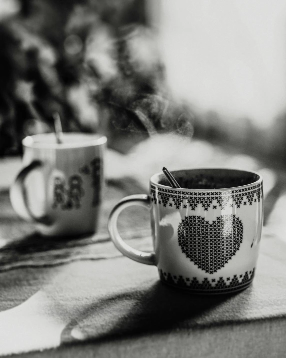 a couple of cups sitting on top of a table, a black and white photo, pexels contest winner, hearts, seasonal, smoking, slightly pixelated