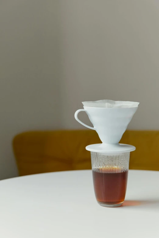 a cup of coffee sitting on top of a table, large opaque visor, japanese collection product, drip, at home