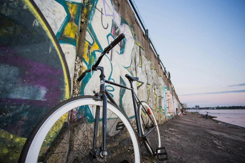 a bicycle leaning against a graffiti covered wall, graffiti, shoreline, profile image, bright rim light, rectangle
