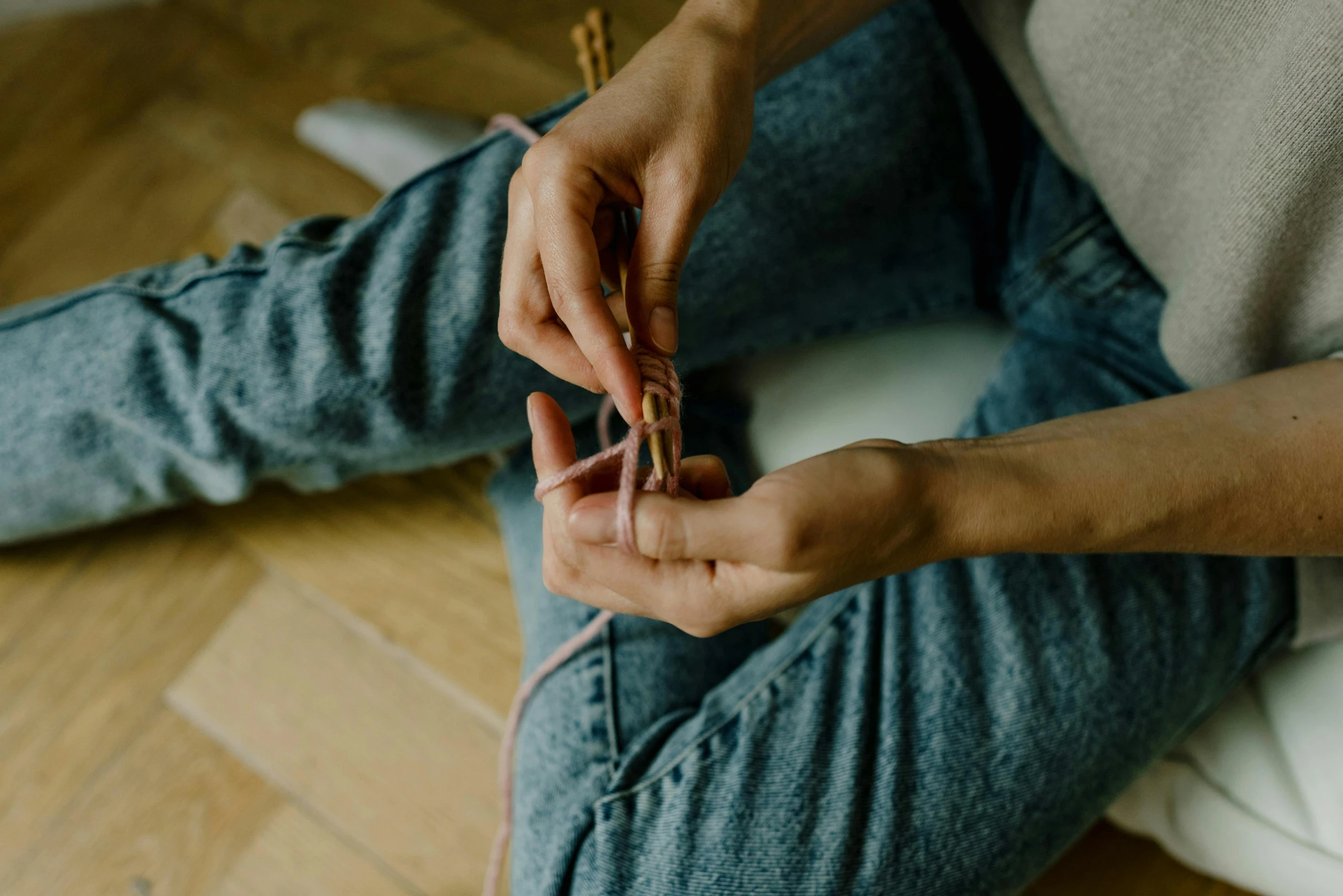 a woman sitting on the floor holding a pair of scissors, a cross stitch, inspired by Sarah Lucas, trending on pexels, arts and crafts movement, wearing jeans, acupuncture treatment, braided cable, thumbnail