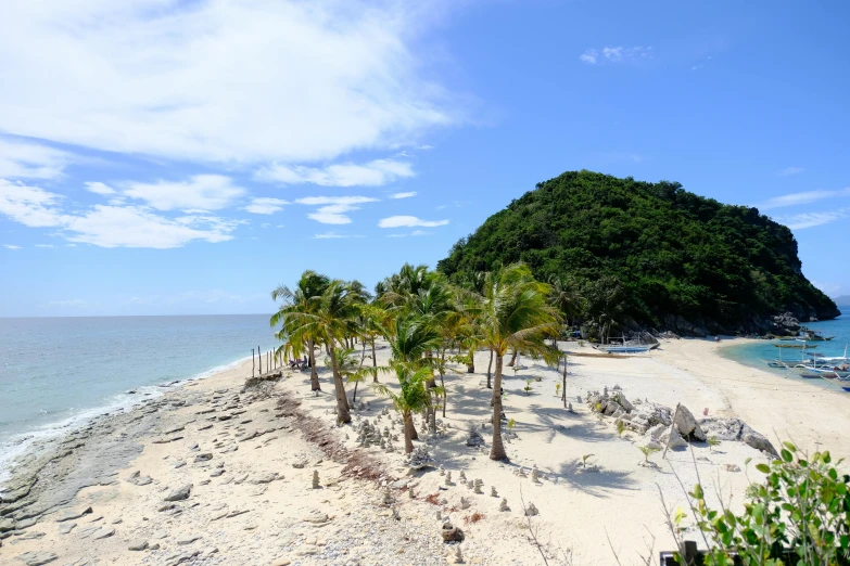 a sandy beach with a small island in the background, by Robbie Trevino, unsplash, sumatraism, dried palmtrees, philippines, slide show, ruins