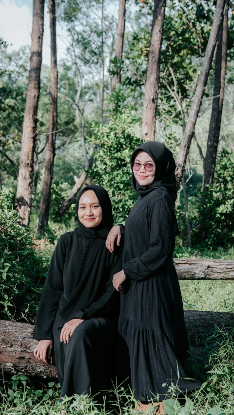 two women sitting on a log in the woods, a picture, by Basuki Abdullah, shutterstock, hurufiyya, wearing in black clothes, portrait n - 9, high quality image