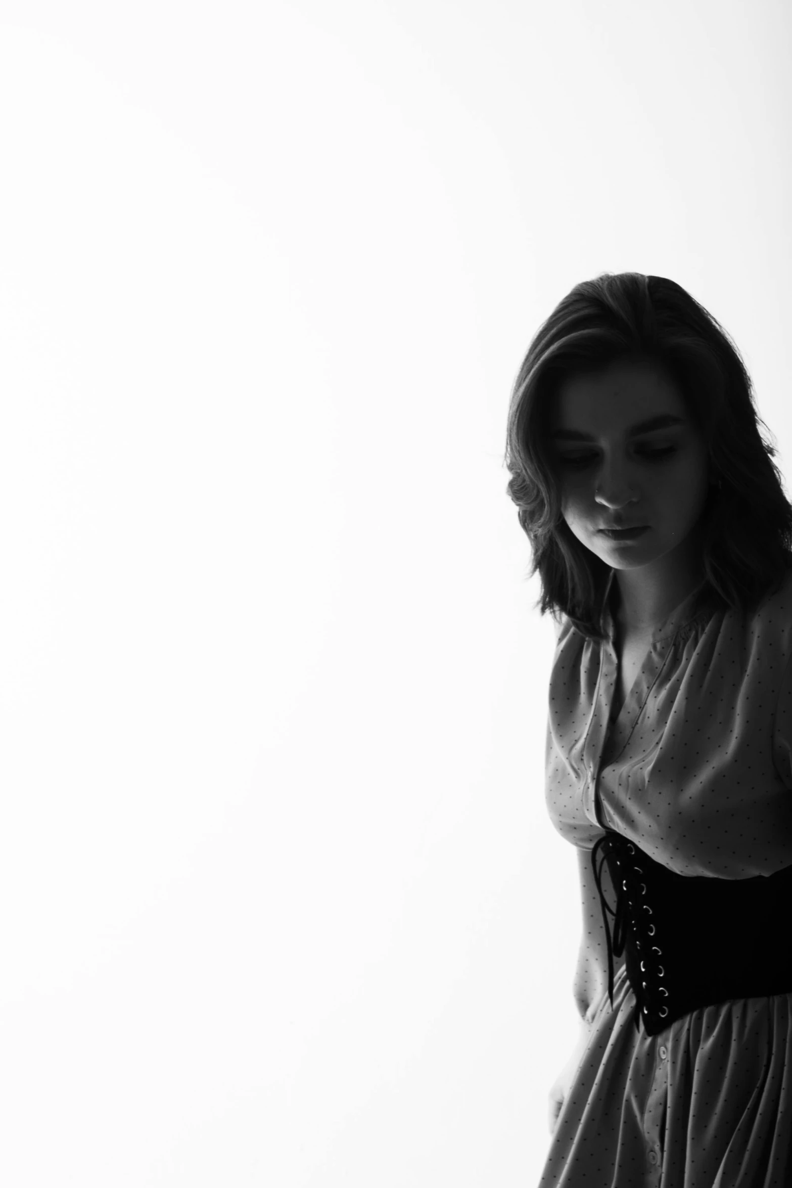 a black and white photo of a woman in a dress, arya stark, 'white background'!!!, in a leather corset, shadows