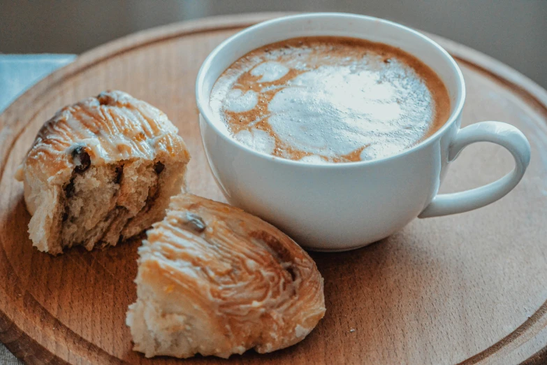 a cup of coffee and a pastry on a plate, by Emma Andijewska, pexels contest winner, renaissance, bread, background image, iced latte, on a wooden tray