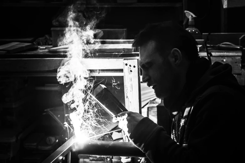a man working on a piece of metal, by Adam Marczyński, pexels contest winner, arbeitsrat für kunst, b&w!, bright sparks, restomod, framing