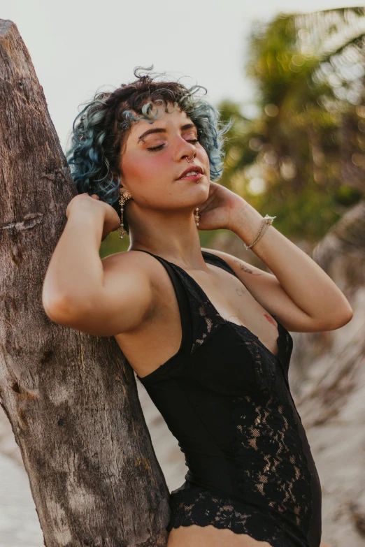 a woman with blue hair leaning against a tree, an album cover, inspired by Elsa Bleda, trending on pexels, renaissance, beautiful tan mexican woman, wearing a black bodysuit, curly pixie hair, beaching