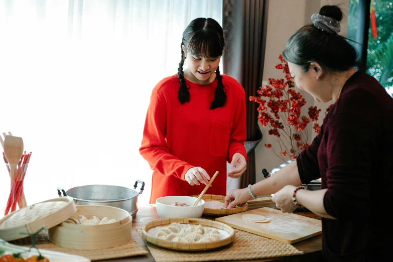 a group of women standing around a table preparing food, inspired by Qian Du, pexels contest winner, avatar image, steamed buns, family friendly, wearing a red cheongsam