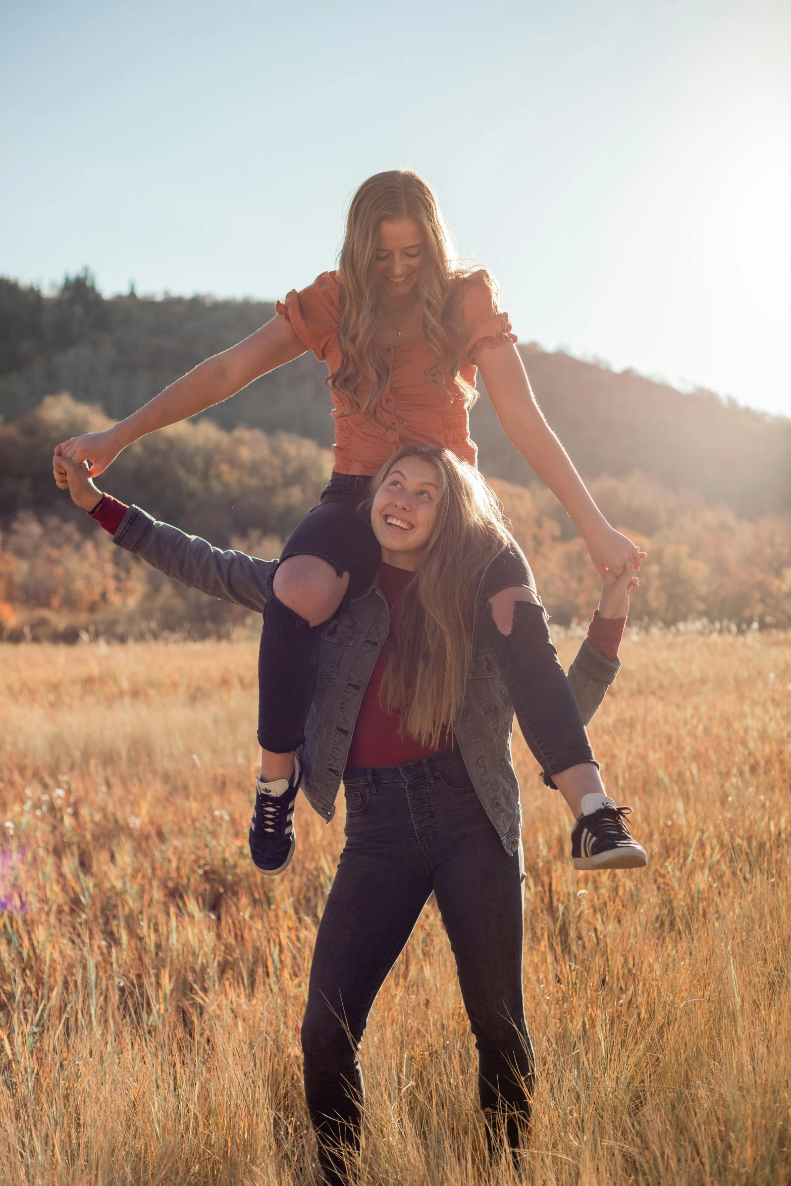 a woman riding on the back of a man in a field, trending on pexels, high school girls, happy friend, hanging, kailee mandel