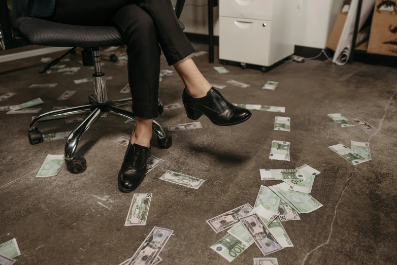 a woman sitting on top of a chair covered in money, by Daniel Lieske, pexels contest winner, black loafers, sitting in dean's office, 🤬 🤮 💕 🎀, bank robbery