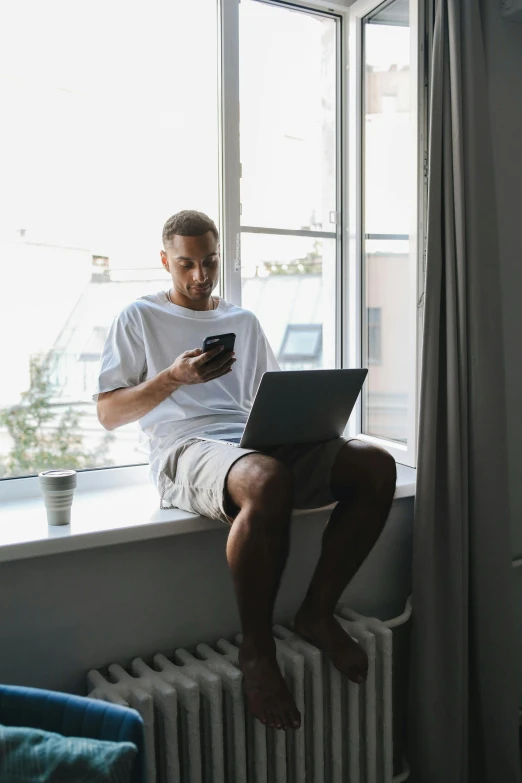 a man sitting on a window sill looking at his cell phone, trending on pexels, happening, sitting in front of computer, someone sits in bed, avatar image, working out