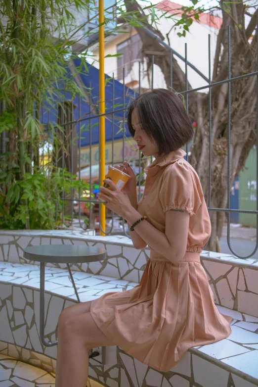 a woman sitting on a bench holding a drink, pale orange colors, ulzzang, profile image, may)