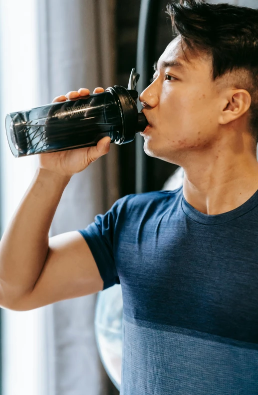 a man in a blue shirt drinking from a bottle, pexels contest winner, she is wearing a black tank top, bursting with muscles, half asian, textured