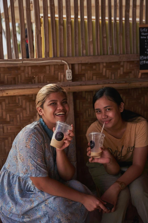 a couple of women sitting next to each other, by Jessie Algie, pexels contest winner, sumatraism, iced latte, square, thanks, with black