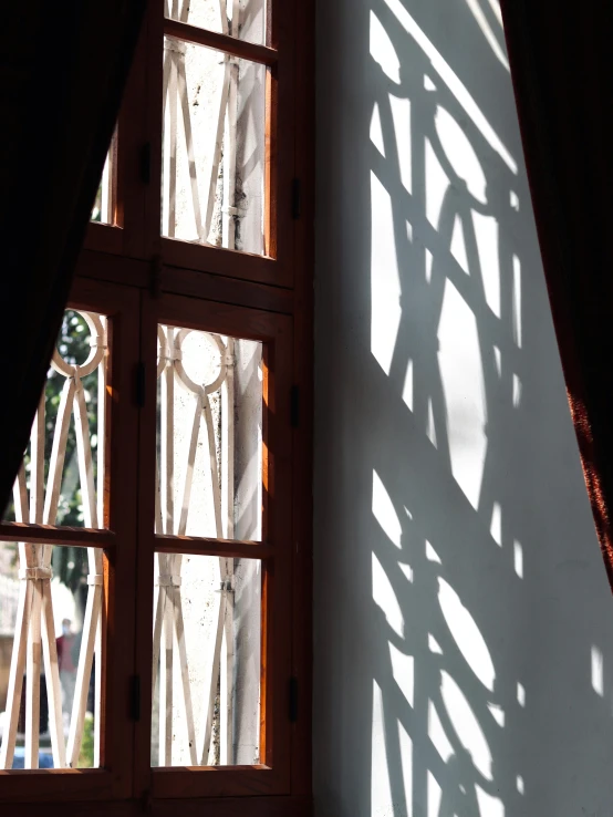 a close up of a window with a curtain, inspired by Riad Beyrouti, light and space, shadows from trees, sun lighting