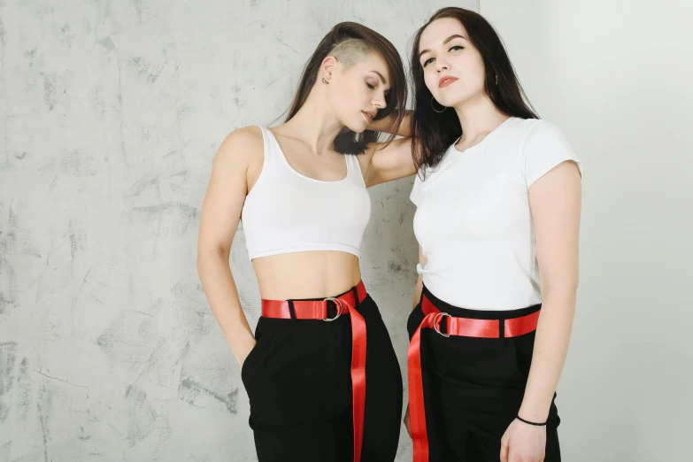 a couple of women standing next to each other, inspired by Wang Duo, trending on pexels, black red white clothes, croptop, belt, with pale skin