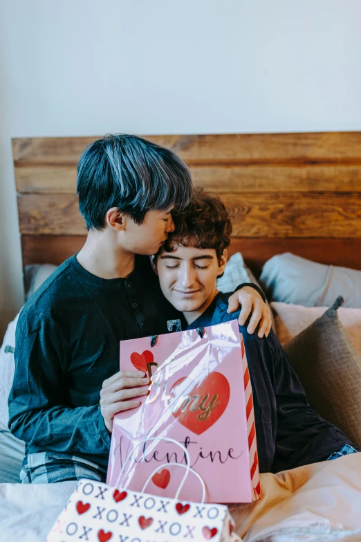 a couple of young men sitting on top of a bed, toy package, pride month, two men hugging, taejune kim