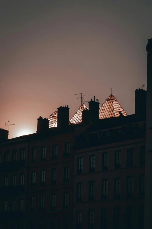 the sun is setting behind the roof of a building, by Raphaël Collin, pexels contest winner, renaissance, moody dim faint lighting, geodesic domes, view from the streets, low quality photo