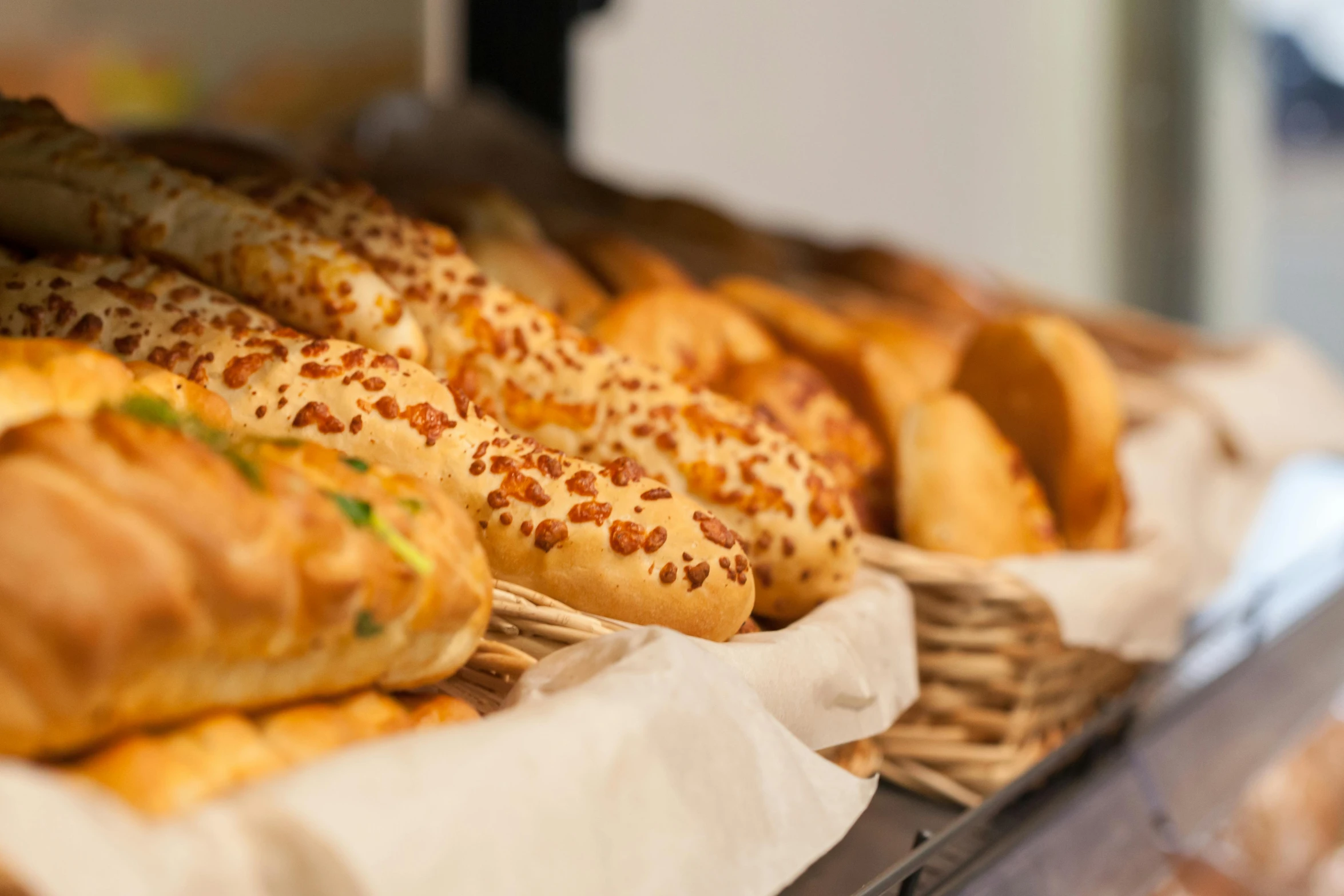 a display case filled with lots of different types of bread, by Adam Marczyński, unsplash, realism, eating garlic bread, closeup at the food, calzone zone, thumbnail