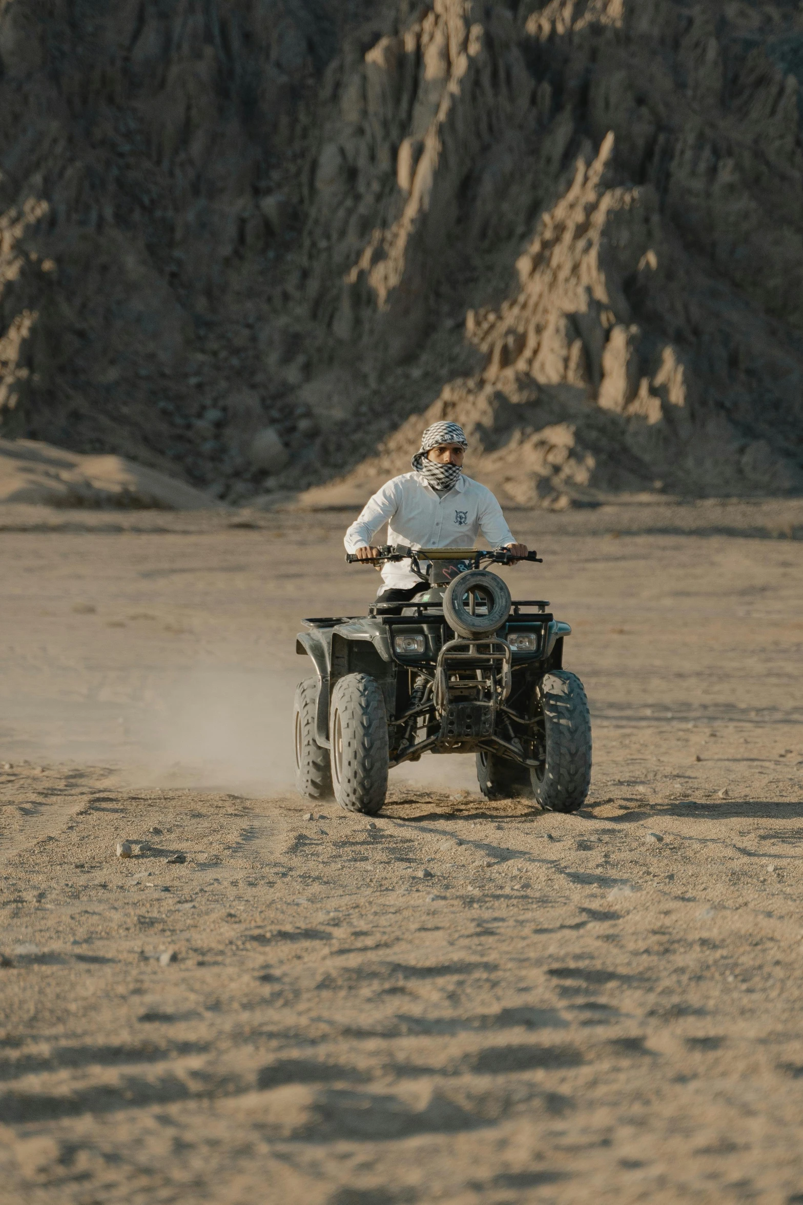 a man riding a four wheeler in the desert, coloured photo, looking serious, egyptian setting, grey