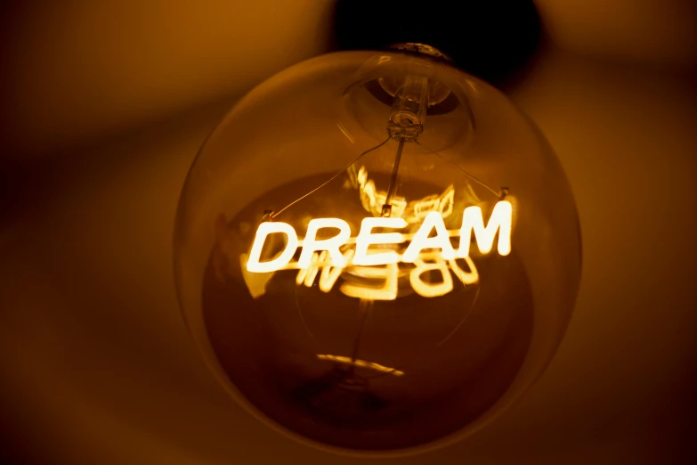 a light bulb with the word dream written on it, unsplash, ambient amber light, light paint, i dream on, medium close up shot