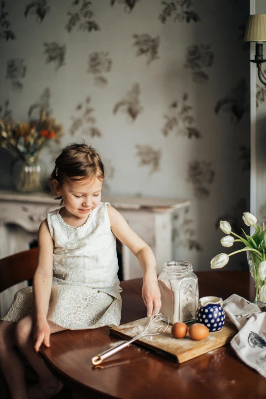 a little girl that is sitting at a table, inspired by Elsa Beskow, pexels contest winner, ingredients on the table, grey, warm spring, delicate patterned