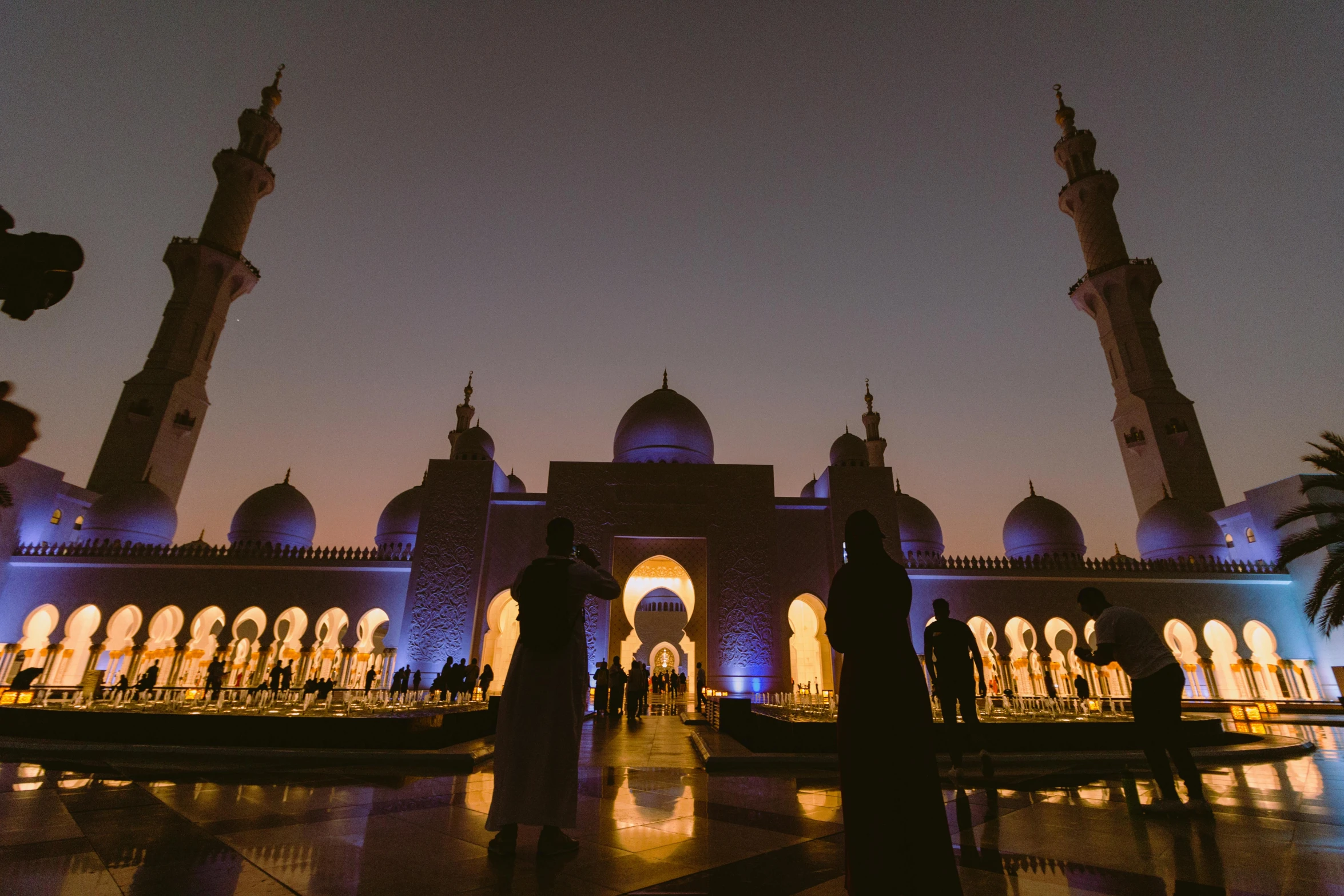 a group of people standing in front of a large building, by Julia Pishtar, pexels contest winner, hurufiyya, arabian night, parks and monuments, arab inspired, lamps on ground