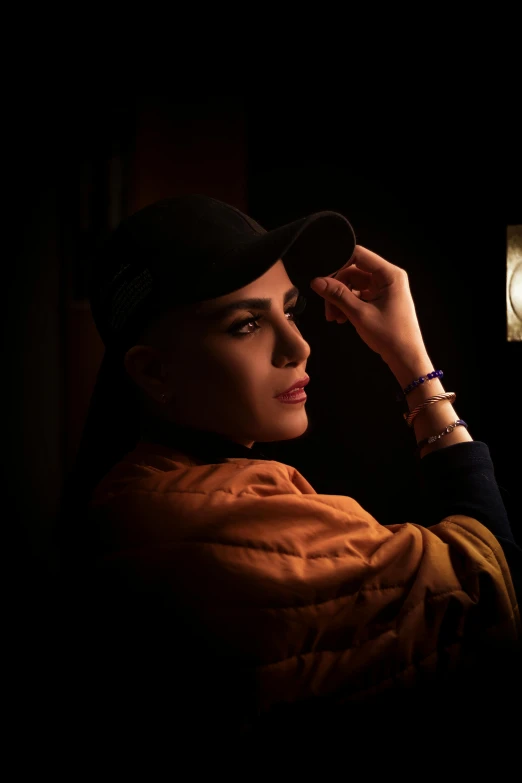 a woman adjusts her hat in the dark, an album cover, inspired by Elsa Bleda, trending on pexels, portait of haifa wehbe, ambient amber light, concept photoset, portrait of natalie portman
