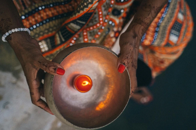 a woman holding a metal bowl with a lit candle in it, pexels contest winner, visual art, songlines, corals are gemstones, instagram post, african sybil