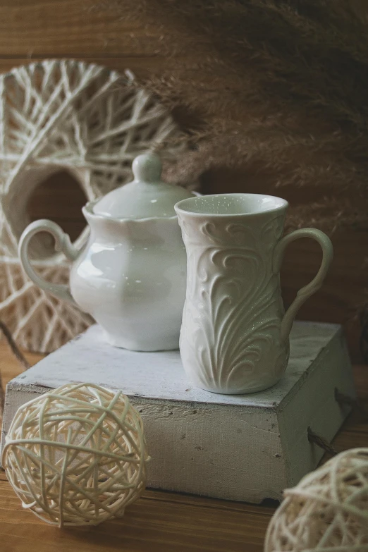 a white vase sitting on top of a stack of books, teapots, intricate texture, product photography, square