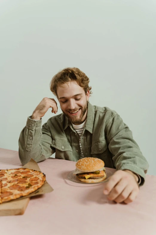 a man sitting at a table with two pizzas, a colorized photo, pexels contest winner, plain background, burger on a plate, post malone, satisfied pose