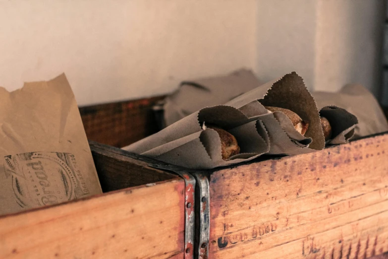 a wooden box filled with food sitting on top of a table, unsplash, private press, inside an old weapon shop, cloth wraps, muted browns, crisps