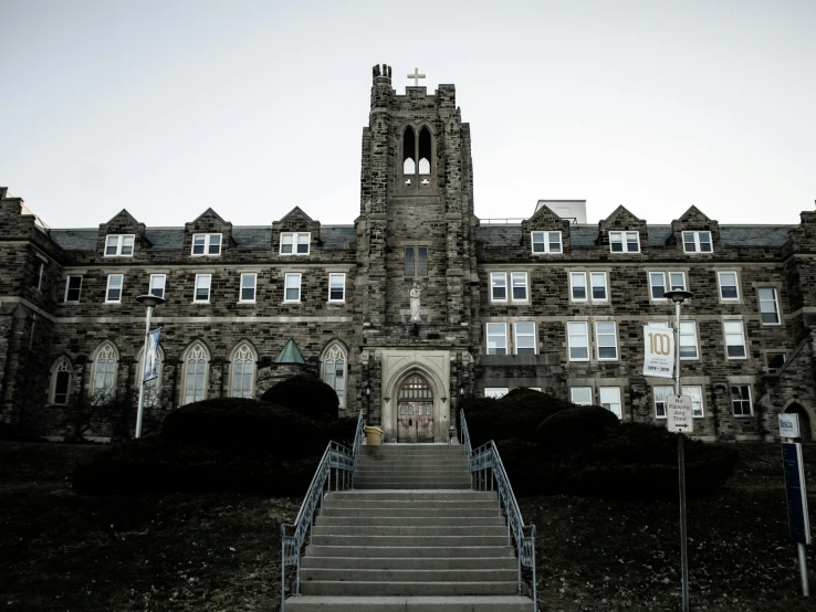 a large stone building with a clock tower, a portrait, by Jacob Burck, pexels, holy cross, pitt, front view dramatic, private academy entrance