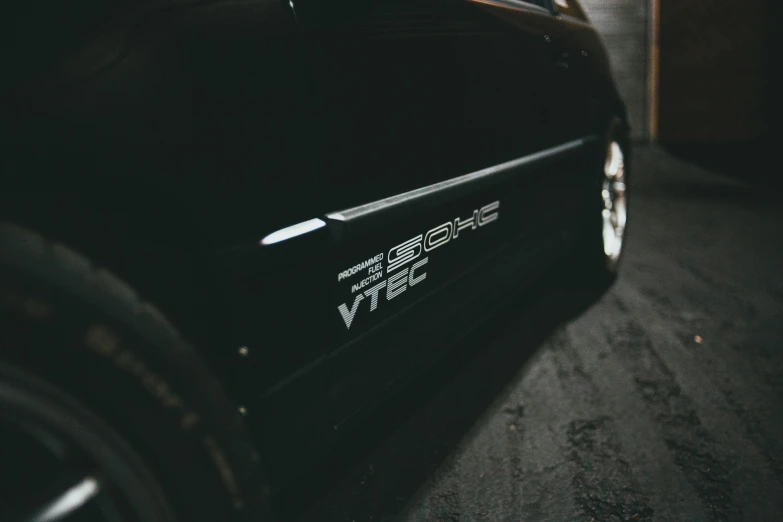 a black sports car parked in a garage, pexels contest winner, simple logo, close up shot from the side, hsv, vtm