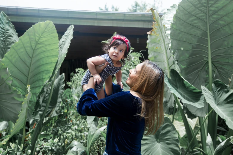 a woman holding a little girl in her arms, pexels contest winner, hurufiyya, lush foliage, avatar image, conde nast traveler photo, various posed