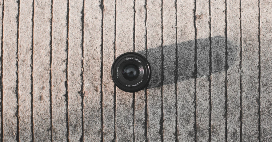 a camera sitting on top of a wooden floor, by Mathias Kollros, unsplash, on the concrete ground, sony lens, today\'s featured photograph 4k, a high angle shot