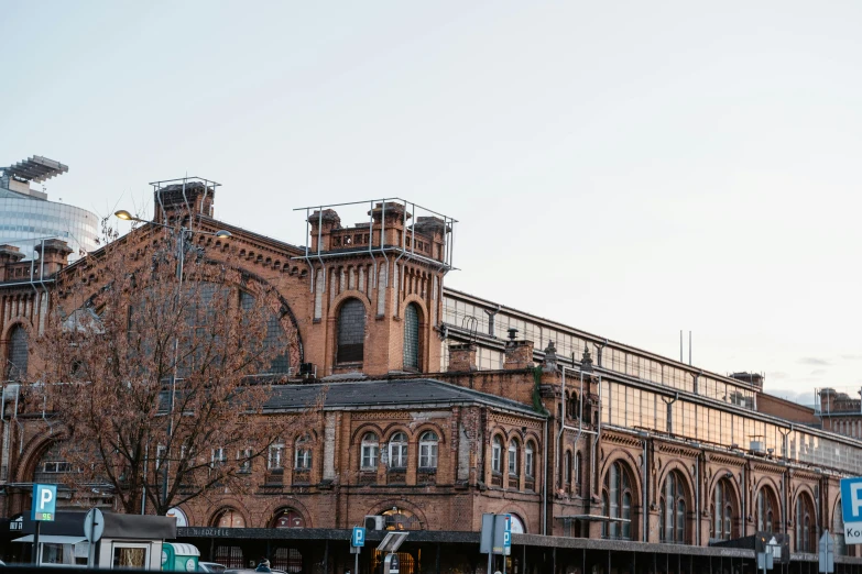 a large brick building sitting on the side of a road, inspired by Modest Urgell, pexels contest winner, art nouveau, train station, markets, kreuzberg, north melbourne street