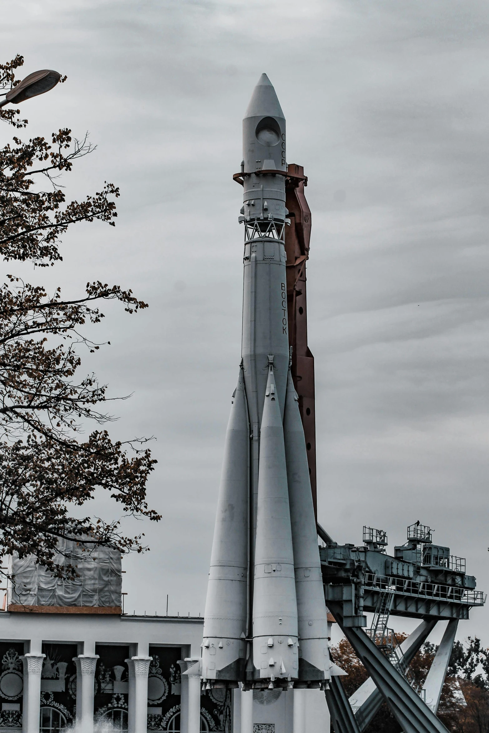 a rocket on display in front of a building, a colorized photo, unsplash, cargo spaceships, high body detail, on a gray background, vostok-1