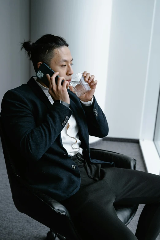 a man sitting in a chair talking on a cell phone, hydration, trending in japan, like andy lau, in office