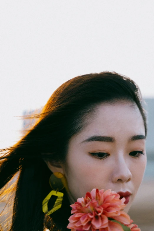 a woman with a flower in her mouth, inspired by Ren Hang, unsplash, sunset lighting, icon, young cute wan asian face, yellow